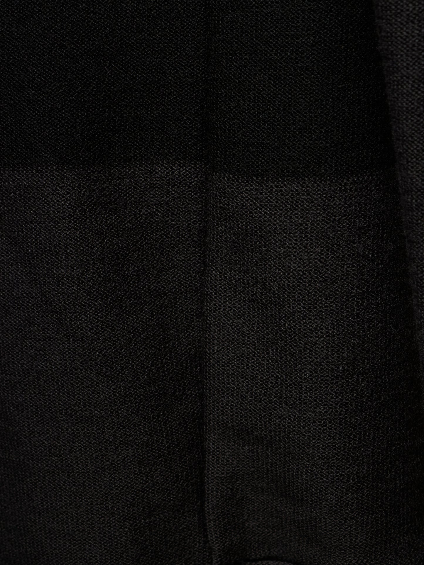 Close-up of a black textured fabric with a subtle woven pattern and a vertical seam.