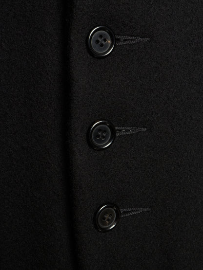 Close-up of a black wool-like fabric garment with three dark buttons aligned vertically.