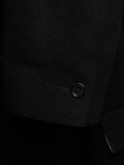 Close-up detail of a black wool or cashmere blazer sleeve cuff, showing the texture of the fabric and a single black button.