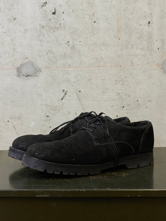 Black suede shoes on a textured surface