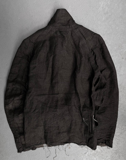 The TaichiMurakami “Coin” Taped Seam Collarless Work Blazer, shown back view on a light gray surface, features frayed edges, a wrinkled textured fabric, and industrial minimalism-inspired details for an unfinished look.