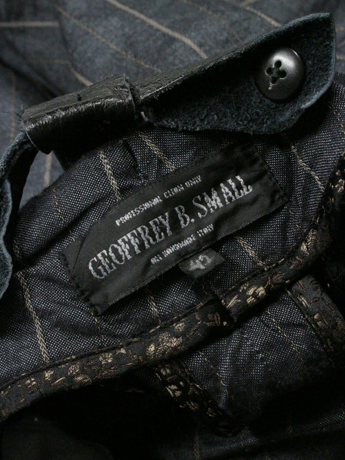 Close-up of a label on a dark fabric garment with a button.