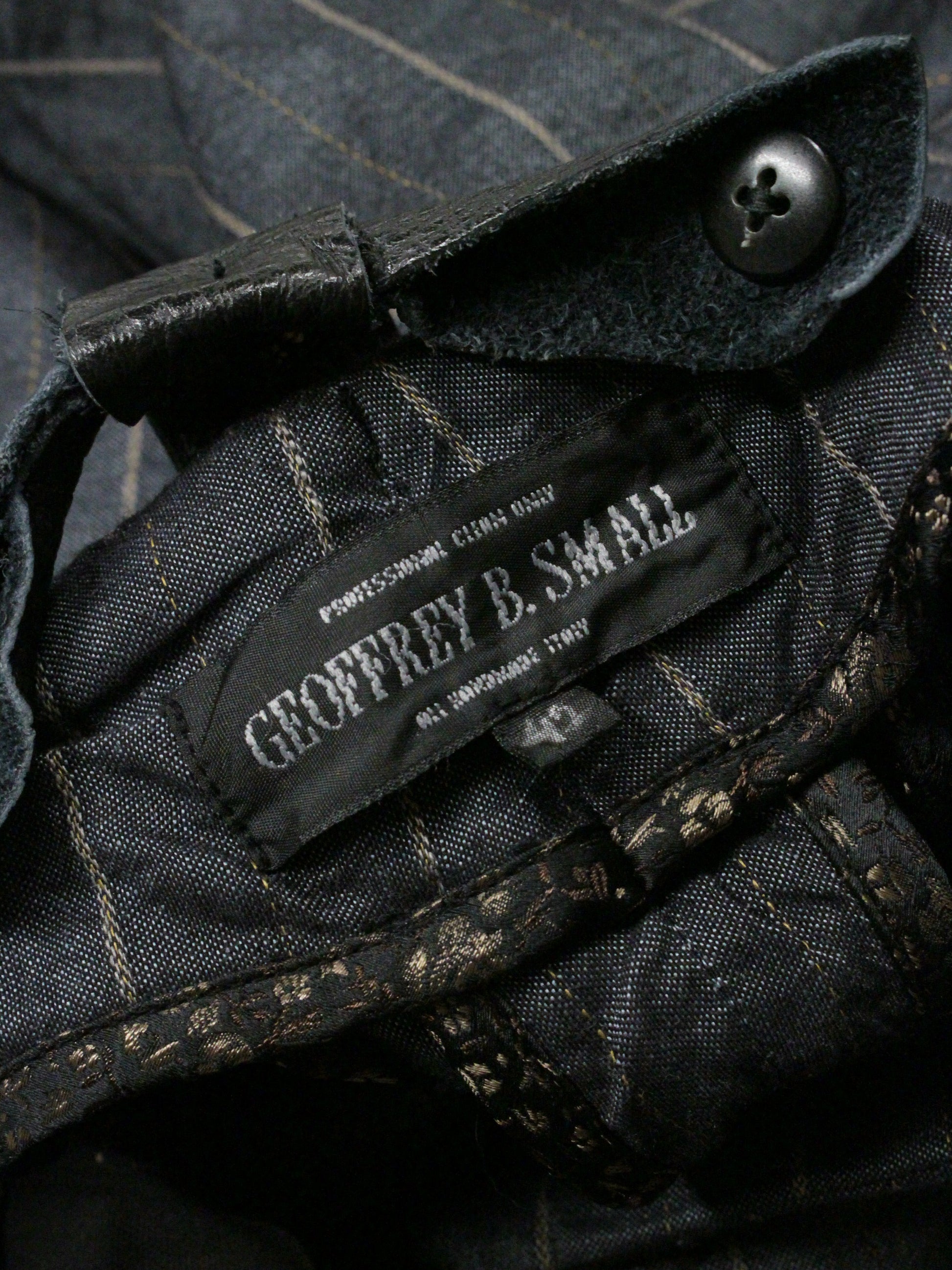 Close-up of a label on a dark fabric garment with a button.