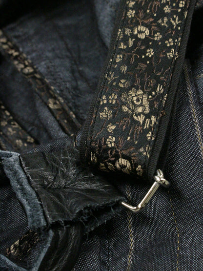 Close-up of a dark denim fabric with floral patterned trim and zipper.