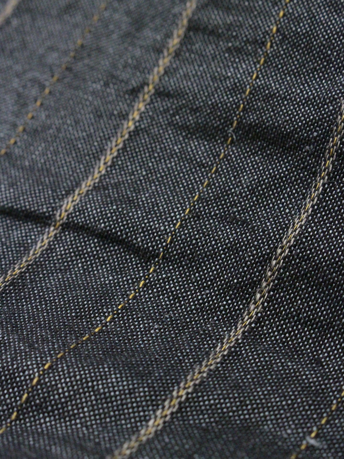 Close-up of dark denim fabric with visible stitching