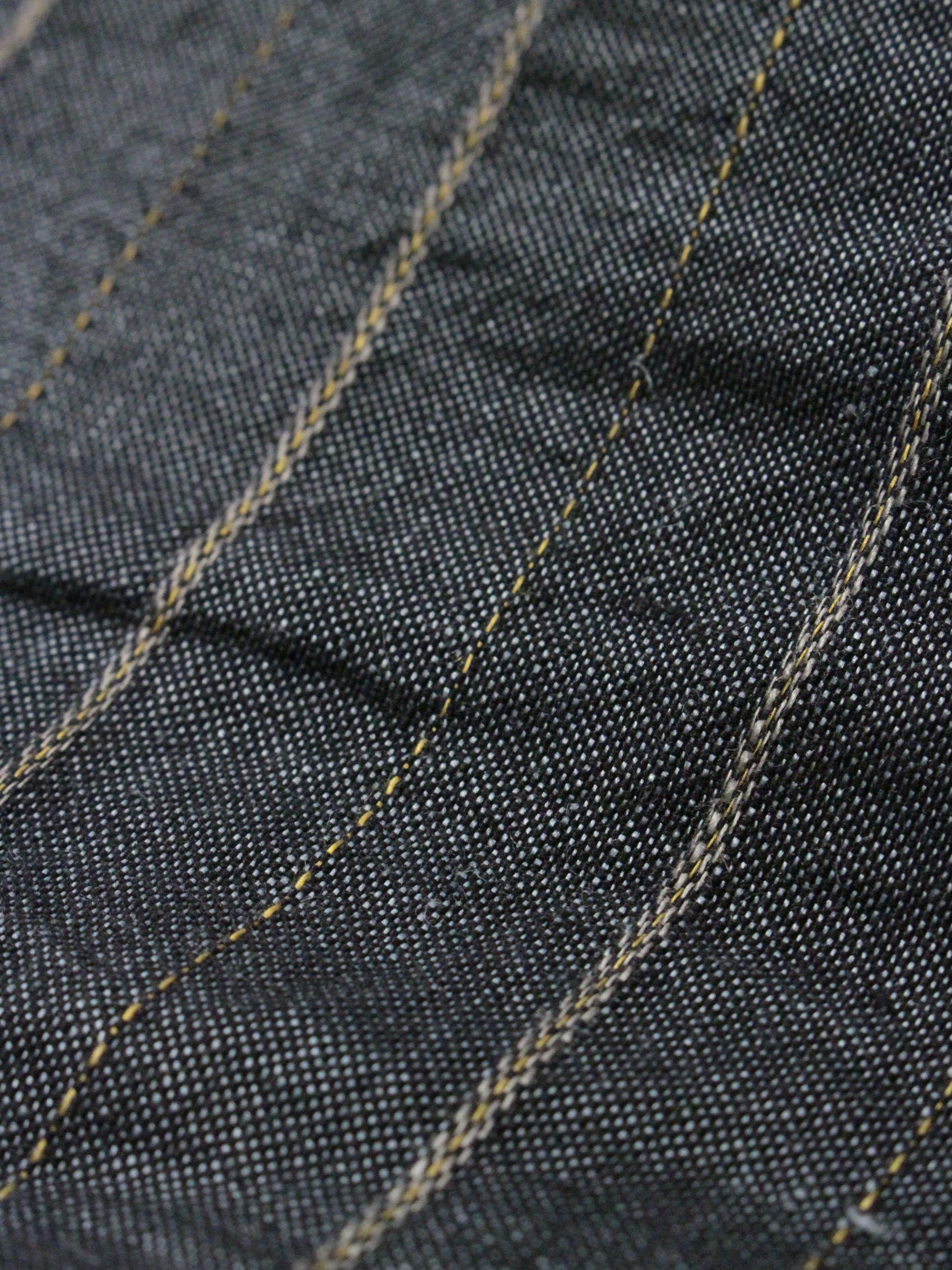 Close-up of dark denim fabric with visible stitching