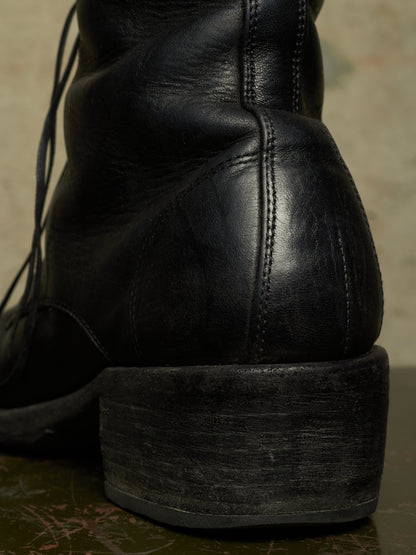Close-up of the back heel and sole of a black leather lace-up boot, showing the stacked platform heel and stitched leather construction.