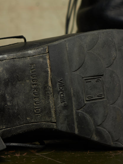 Close-up of the black rubber outsole of a shoe, showing embossed branding and tread details.