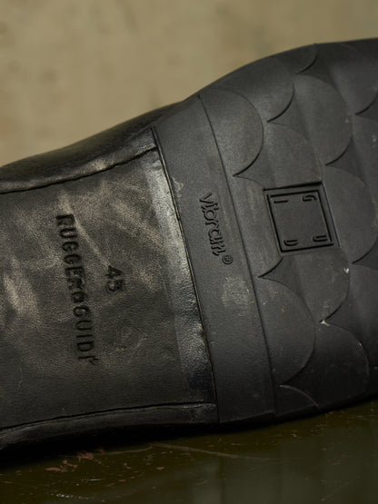 Close-up of the black rubber outsole of a shoe, showing embossed branding and tread details including 'RUGGEDGUIDE' and 'Vespalia'.