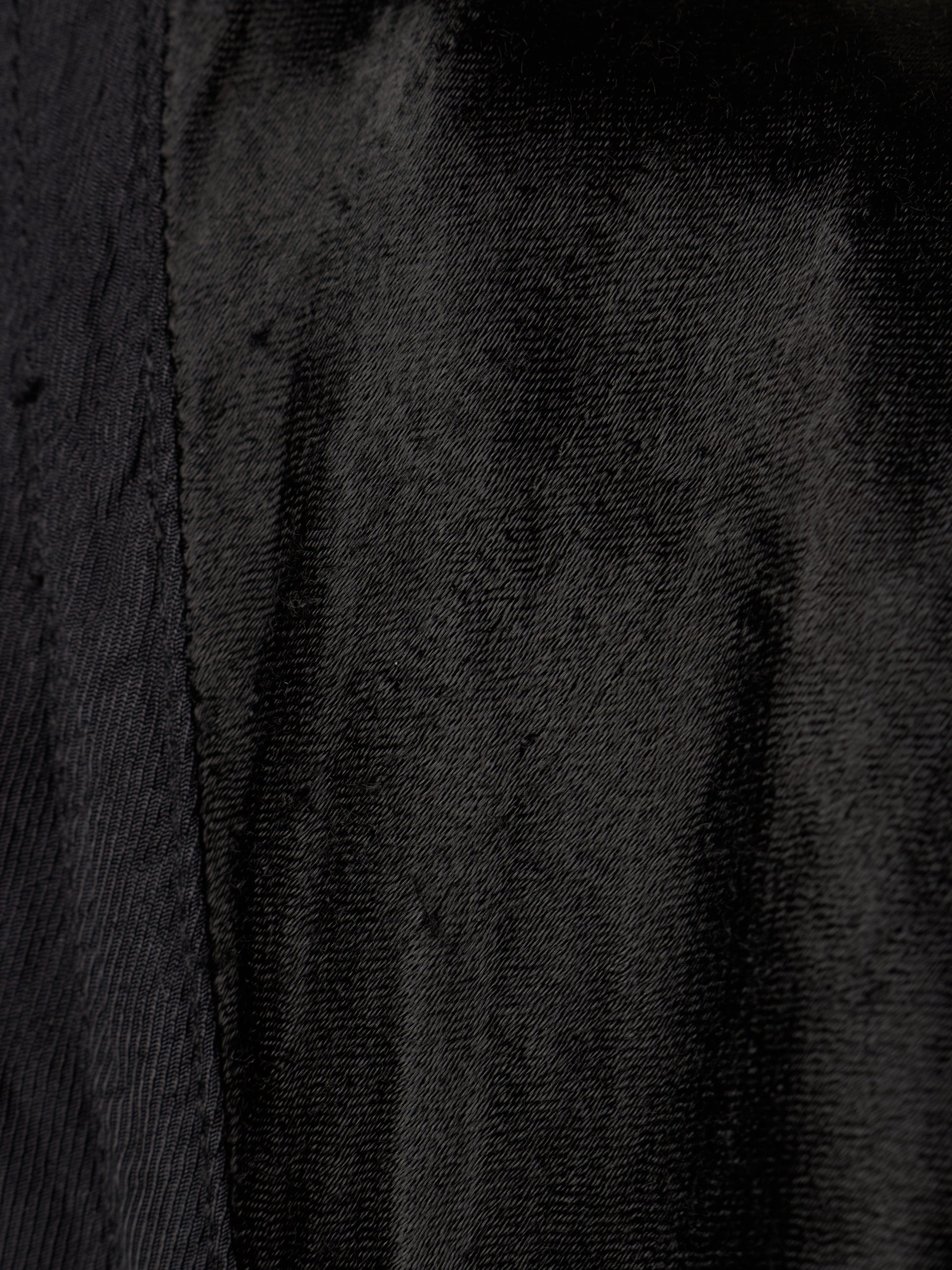 Close-up of a black textured fabric with a visible vertical seam.