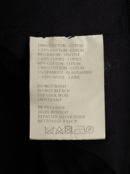 A close-up of a white garment care label sewn onto black fabric, showing text with material percentages and care instructions in English and French.