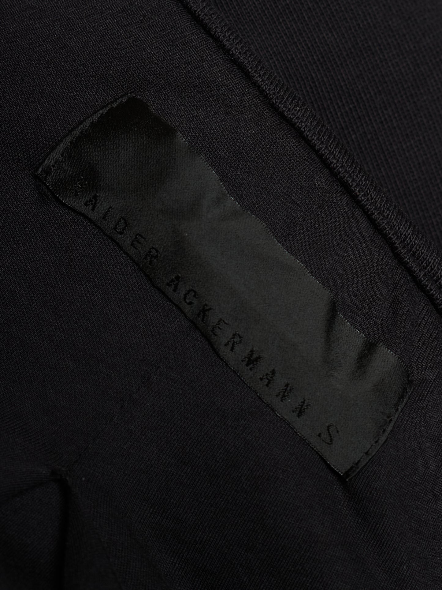 Close-up of a black garment showing a satin brand label that reads 'SALTER ACKERMANN S'.