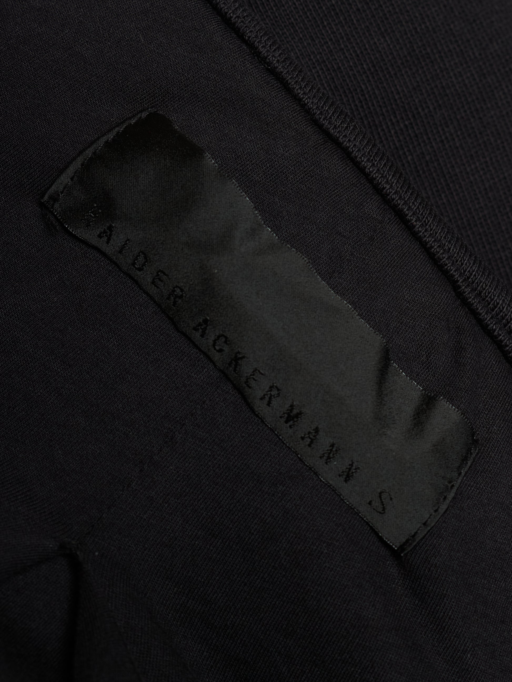 Close-up of a black garment showing a satin brand label that reads 'SALTER ACKERMANN S'.