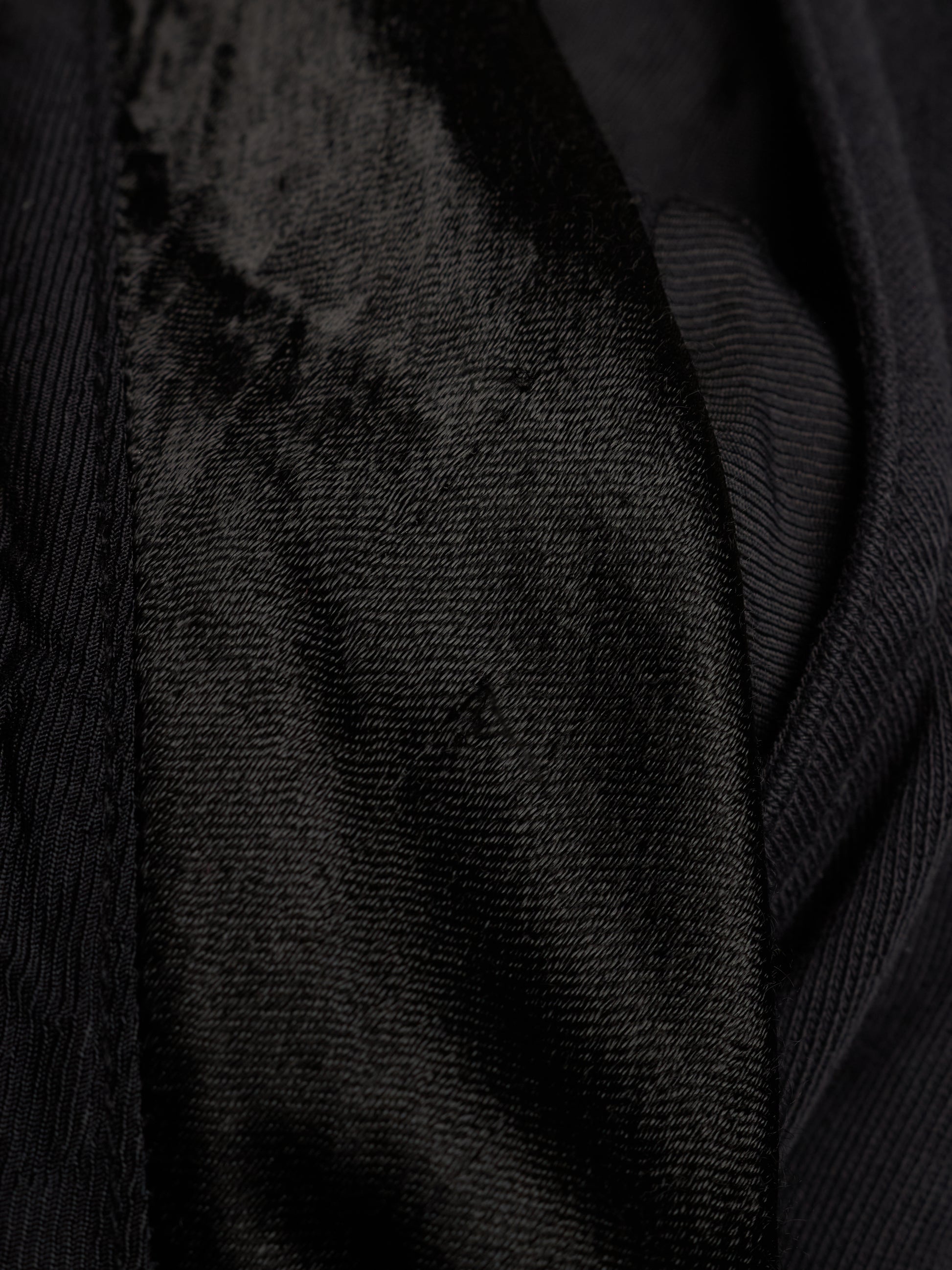 Close-up of a black textured fabric with a ribbed outer material and a plush velvet-like inner panel.