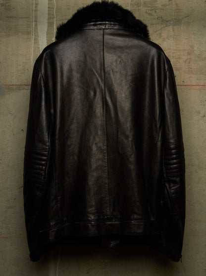 Black leather jacket with a dark fur collar, shown from the back against a textured concrete wall.