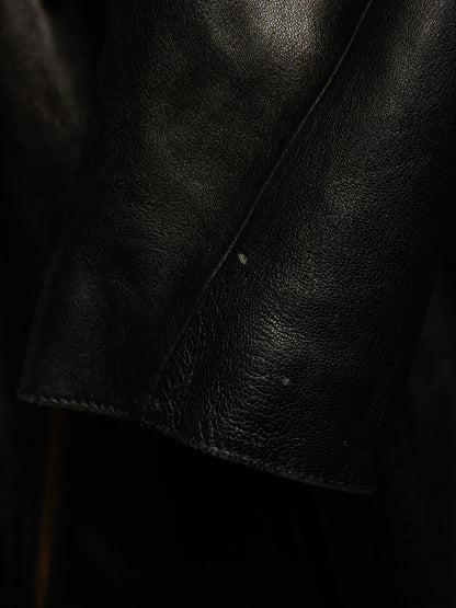 Close-up of a black leather jacket sleeve showing the pebbled texture and stitched cuff.