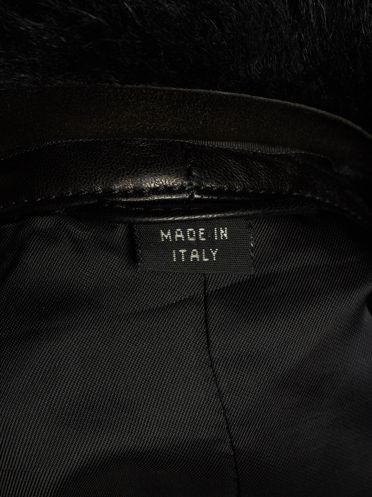 Close-up of the interior collar of a black garment with a black faux-fur trim and a sewn-in label reading 'MADE IN ITALY'.