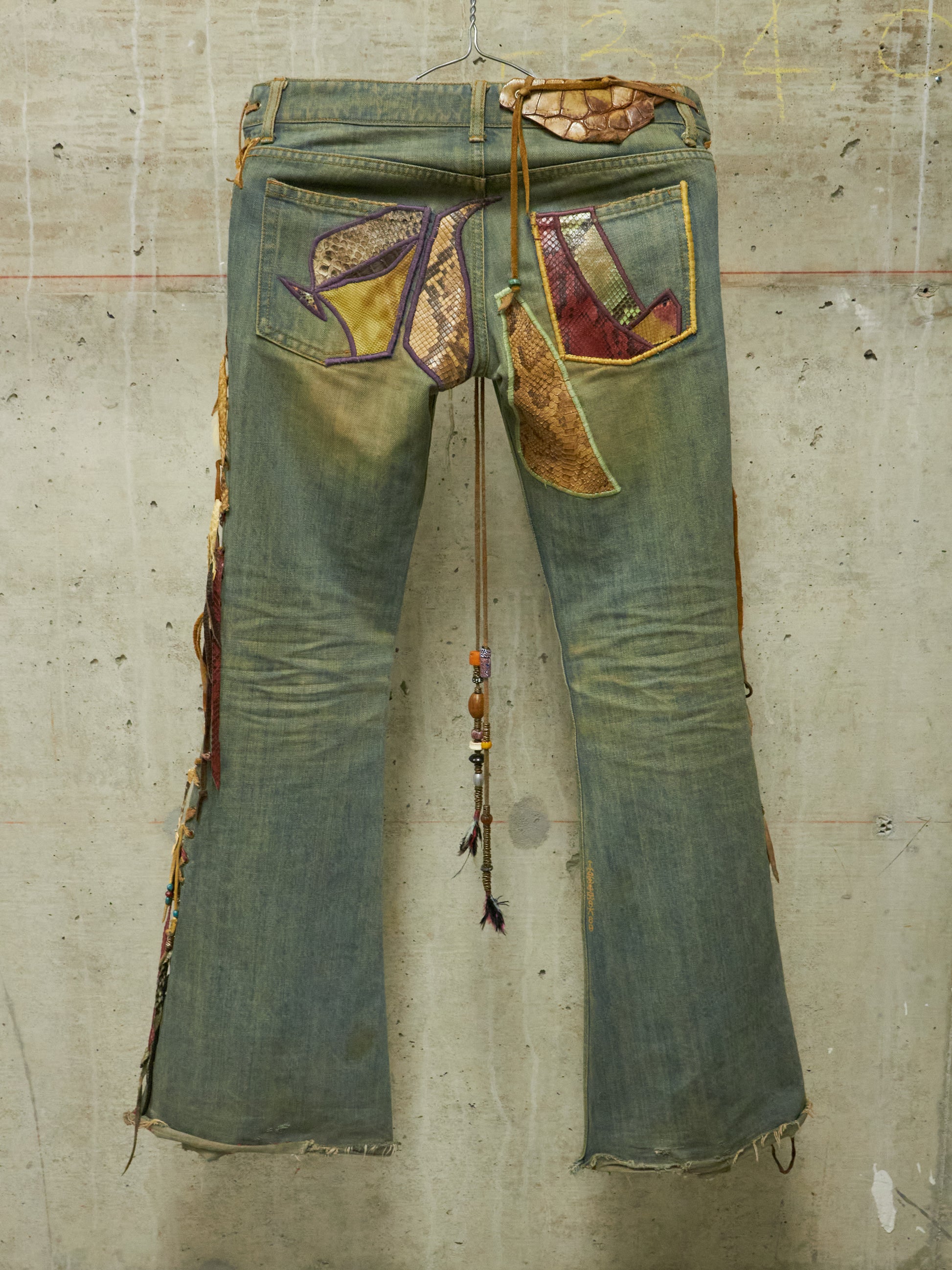 Pair of patchwork jeans on a textured concrete wall