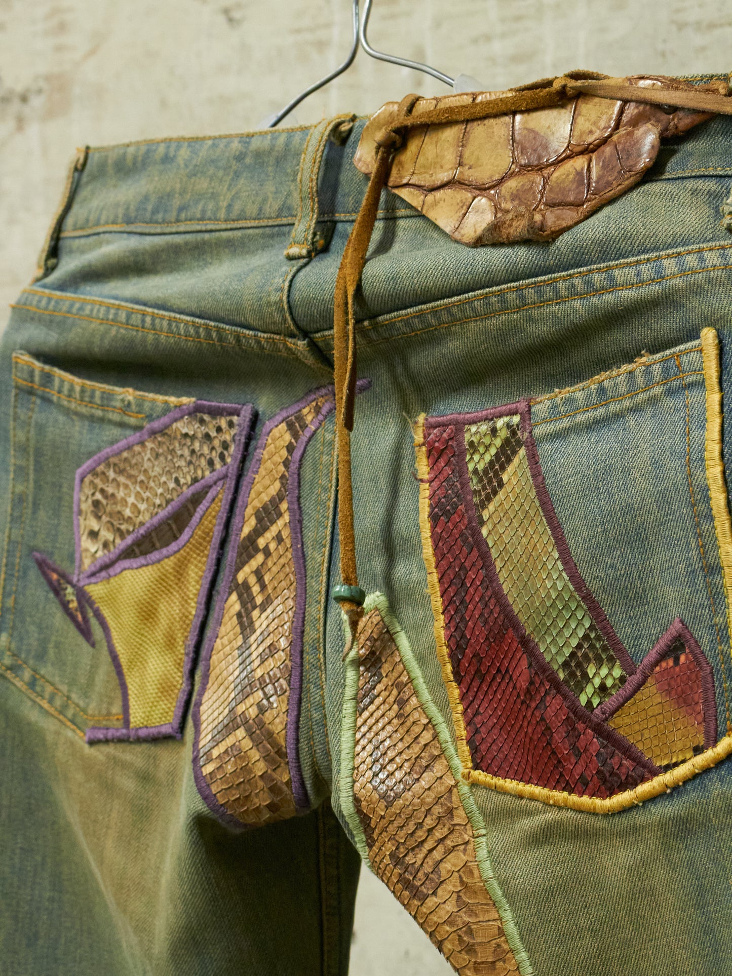 Denim pants with decorative patches on a beige background