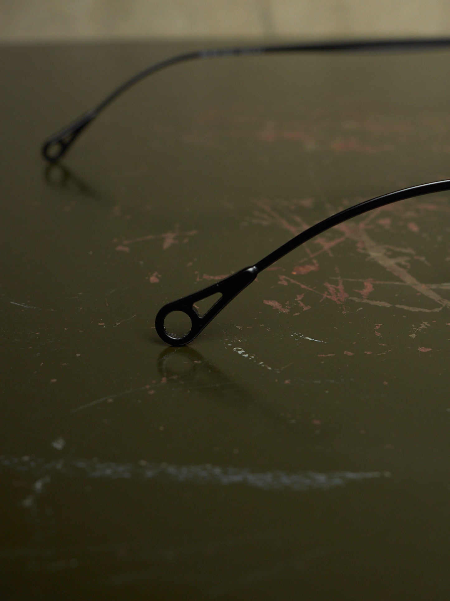 Black metal bicycle frame ends with round dropouts resting on a dark, scratched tabletop.