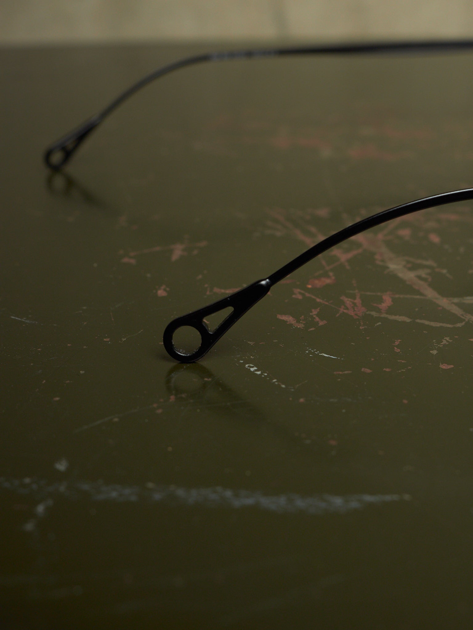 Black metal bicycle frame ends with round dropouts resting on a dark, scratched tabletop.