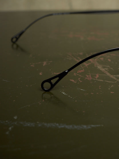 Black metal bicycle frame ends with round dropouts resting on a dark, scratched tabletop.