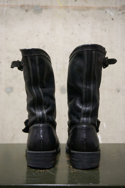 Pair of black leather boots on a concrete surface