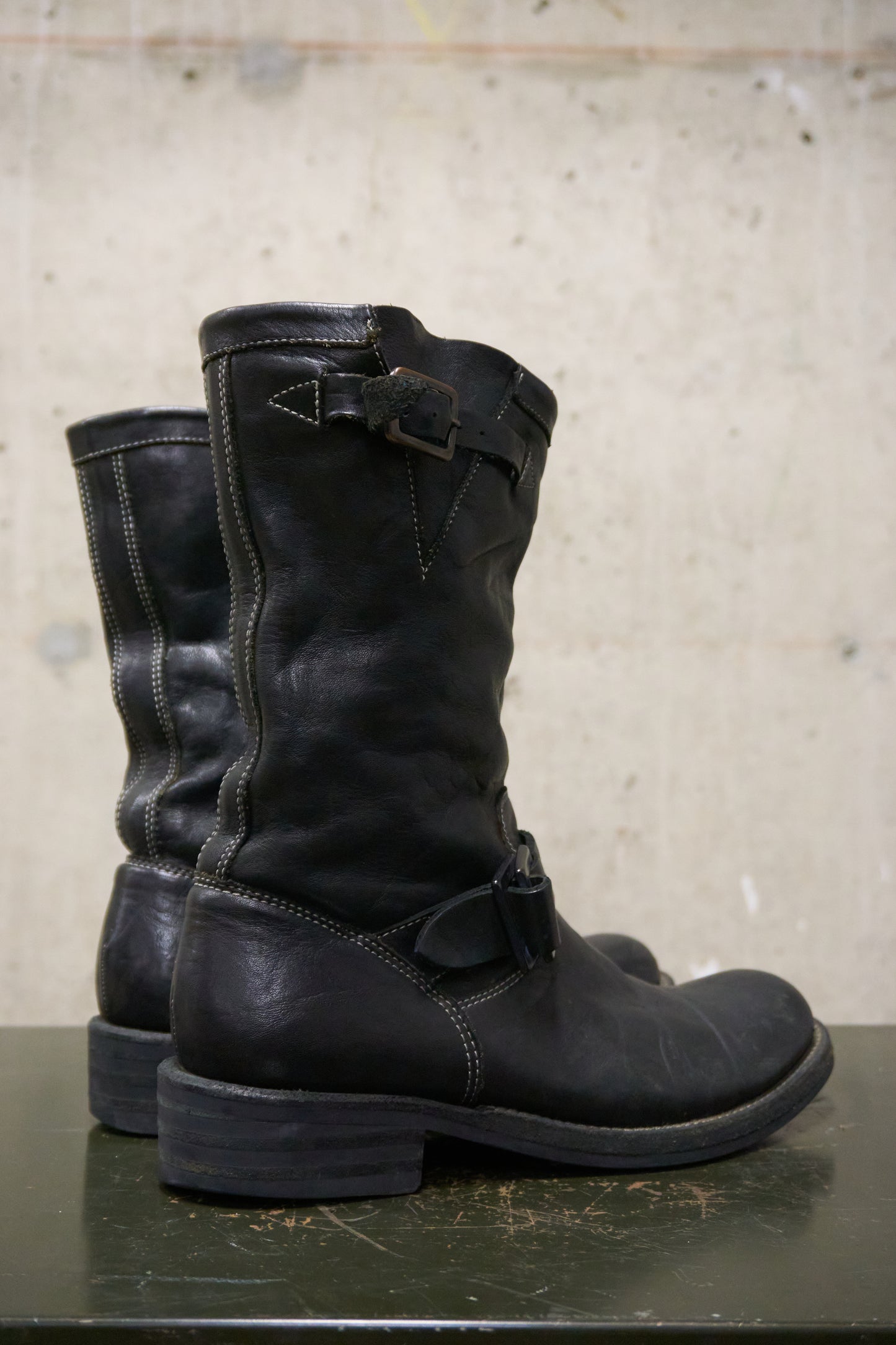 Pair of black leather boots on a concrete surface