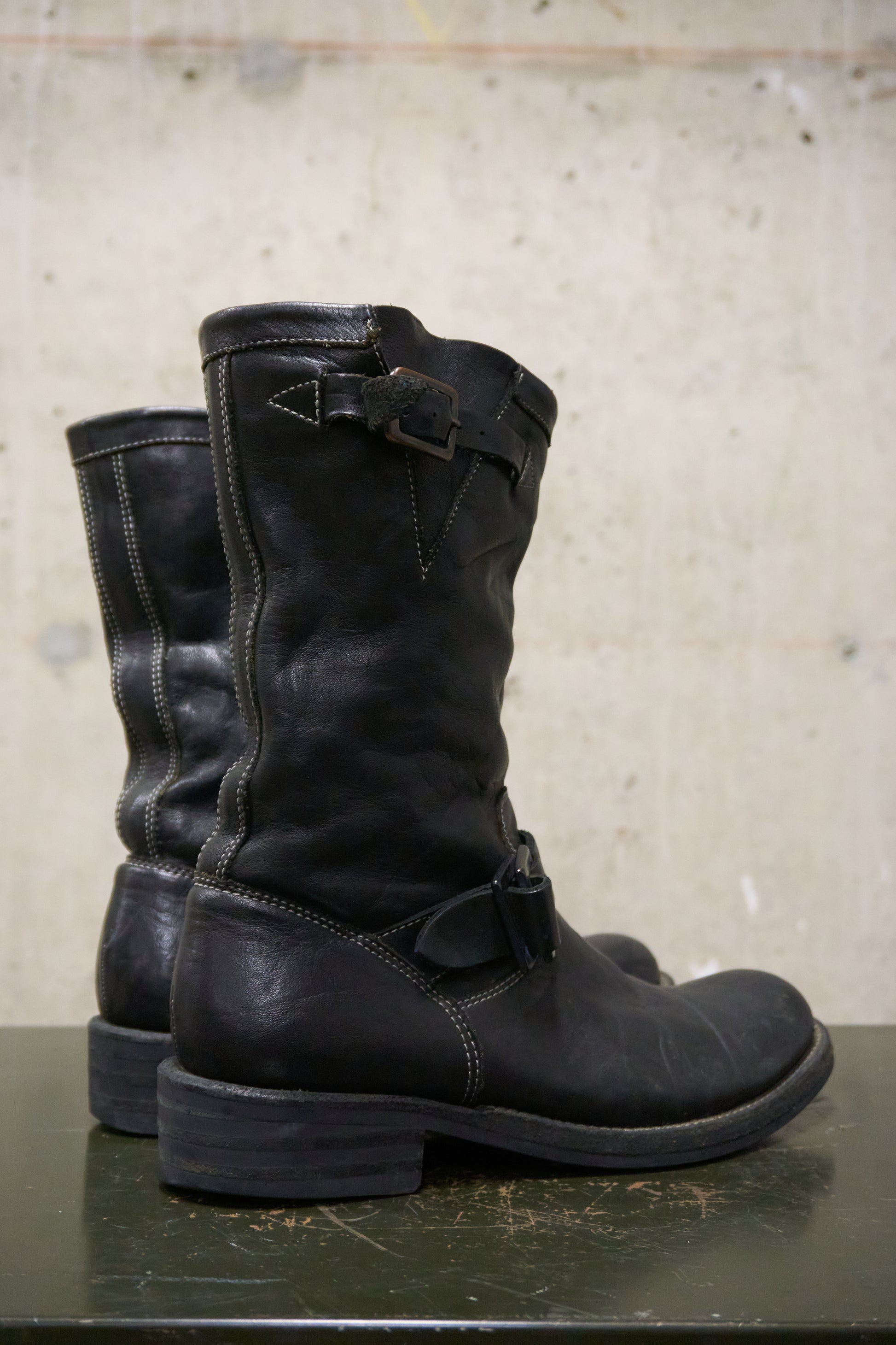 Pair of black leather boots on a concrete surface