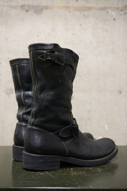 Pair of black leather boots on a concrete surface