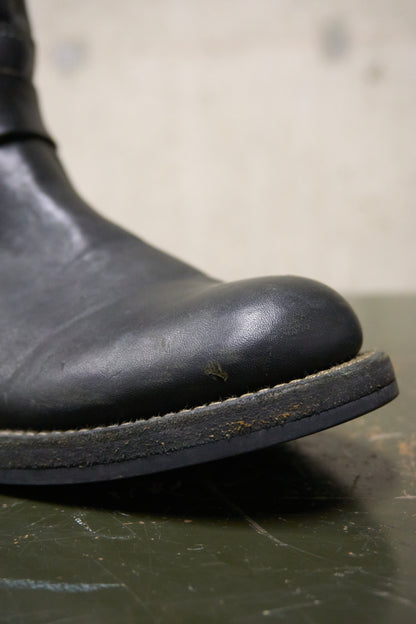 Close-up of a black leather boot sole on a textured surface with a blurred background