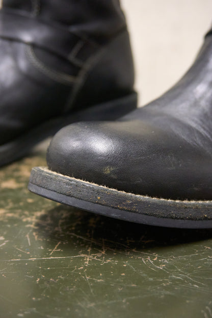 Close-up of a worn black boot on a scratched green surface
