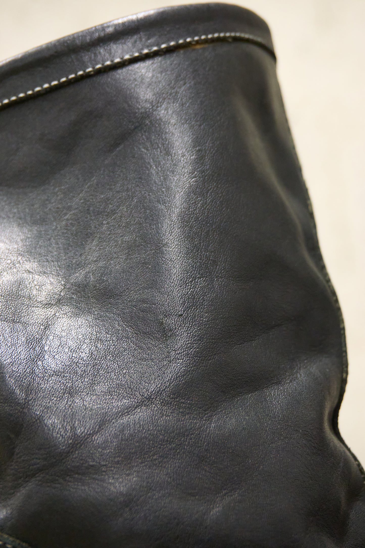 Close-up of a black leather bag with a zipper on a beige background