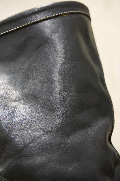 Close-up of a black leather bag with a zipper on a beige background