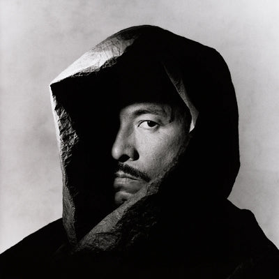 Issey Miyake famous Japanese designer portrait wearing hood on grey background