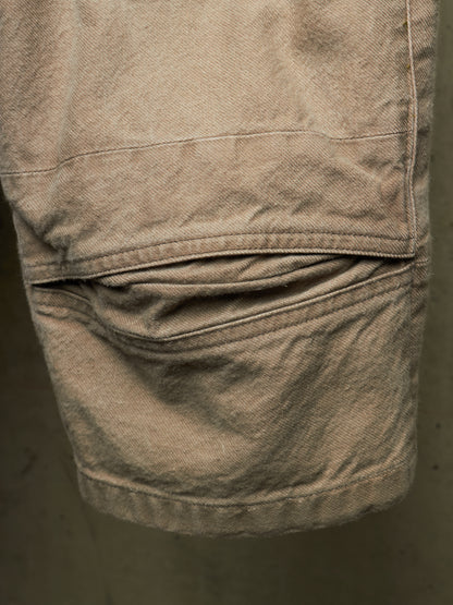Close-up of a beige canvas utility pocket on a pair of shorts, showing the texture of the fabric and the stitching.