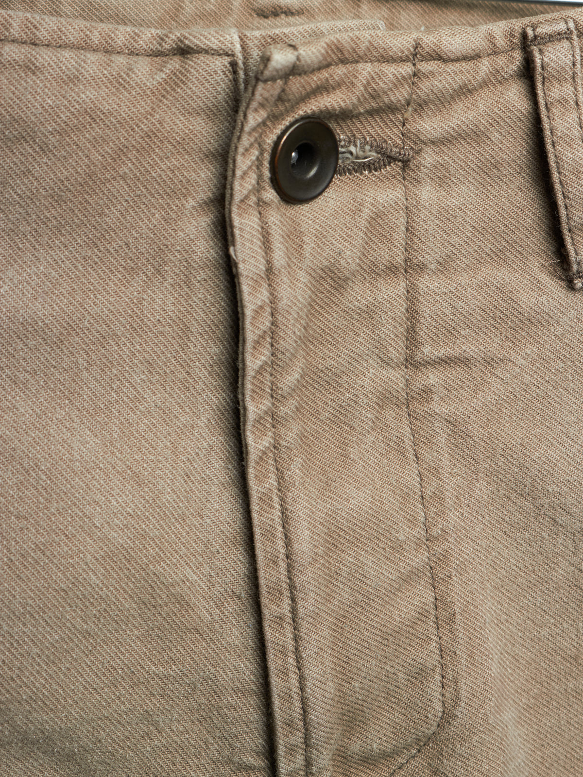 Close-up detail of a pair of brown twill pants showing the button closure and pocket stitching.