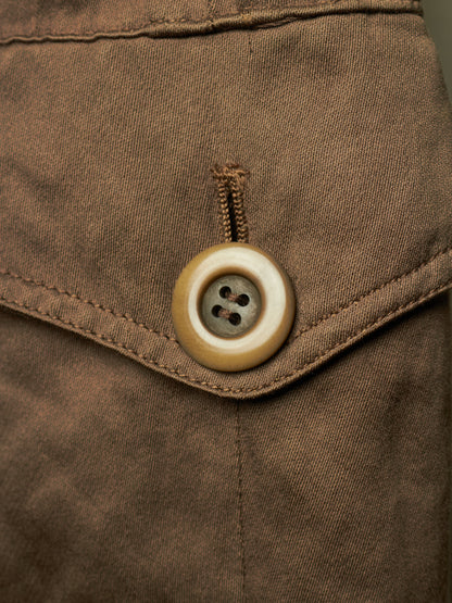 Close-up detail of a brown fabric garment featuring a brown buttoned flap pocket.