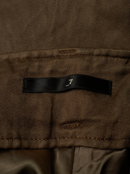 Close-up of a brown fabric garment showing a black fabric label with a small white stylized logo.