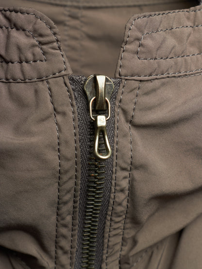 Close-up of a dark brown nylon jacket with a central metal zipper and a silver lobster clasp.