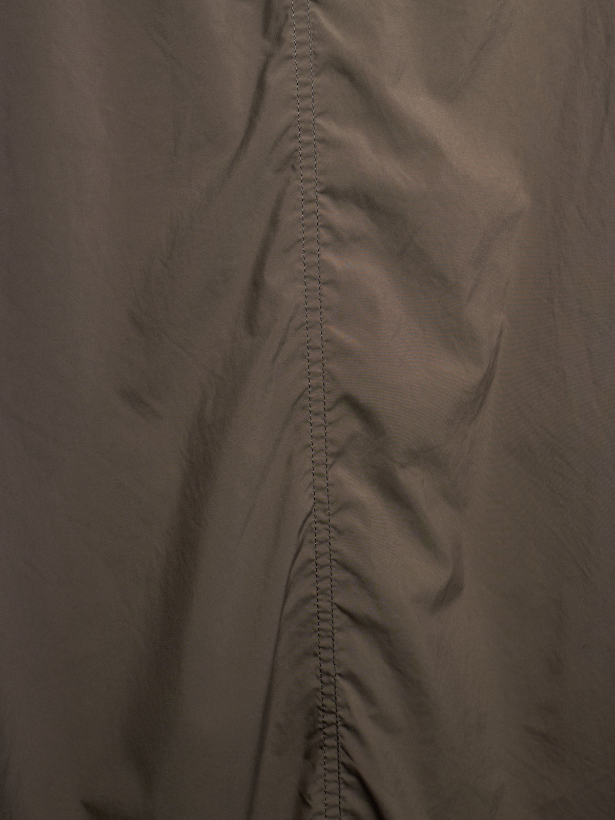 Close-up of a dark taupe-brown fabric with a central vertical seam and stitched edge detail.