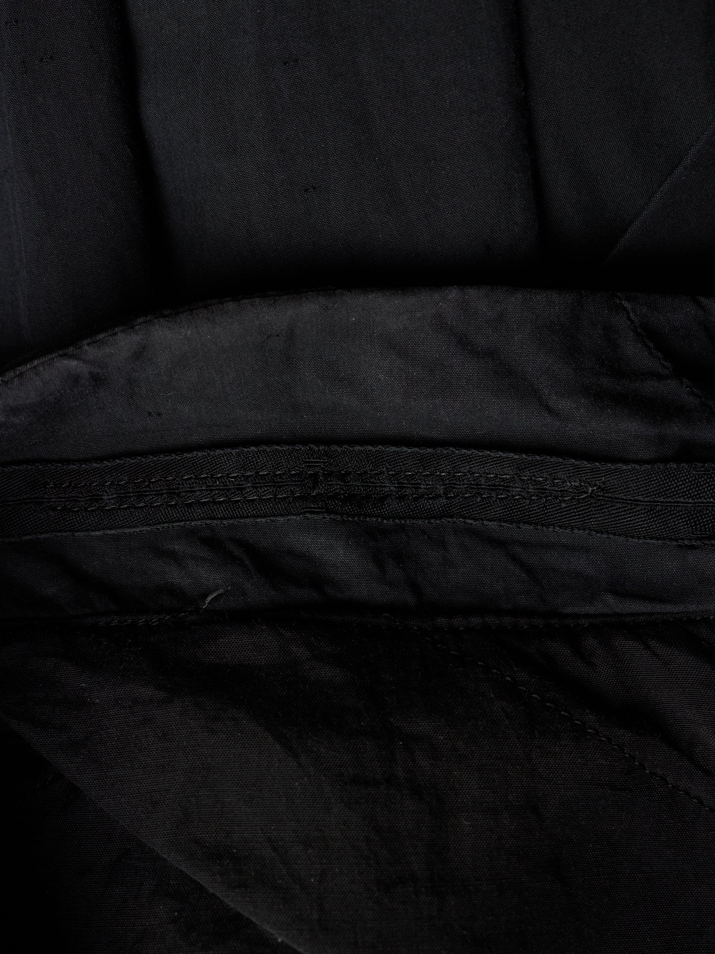 Close-up detail of a black fabric item showing a stitched seam and textured material.