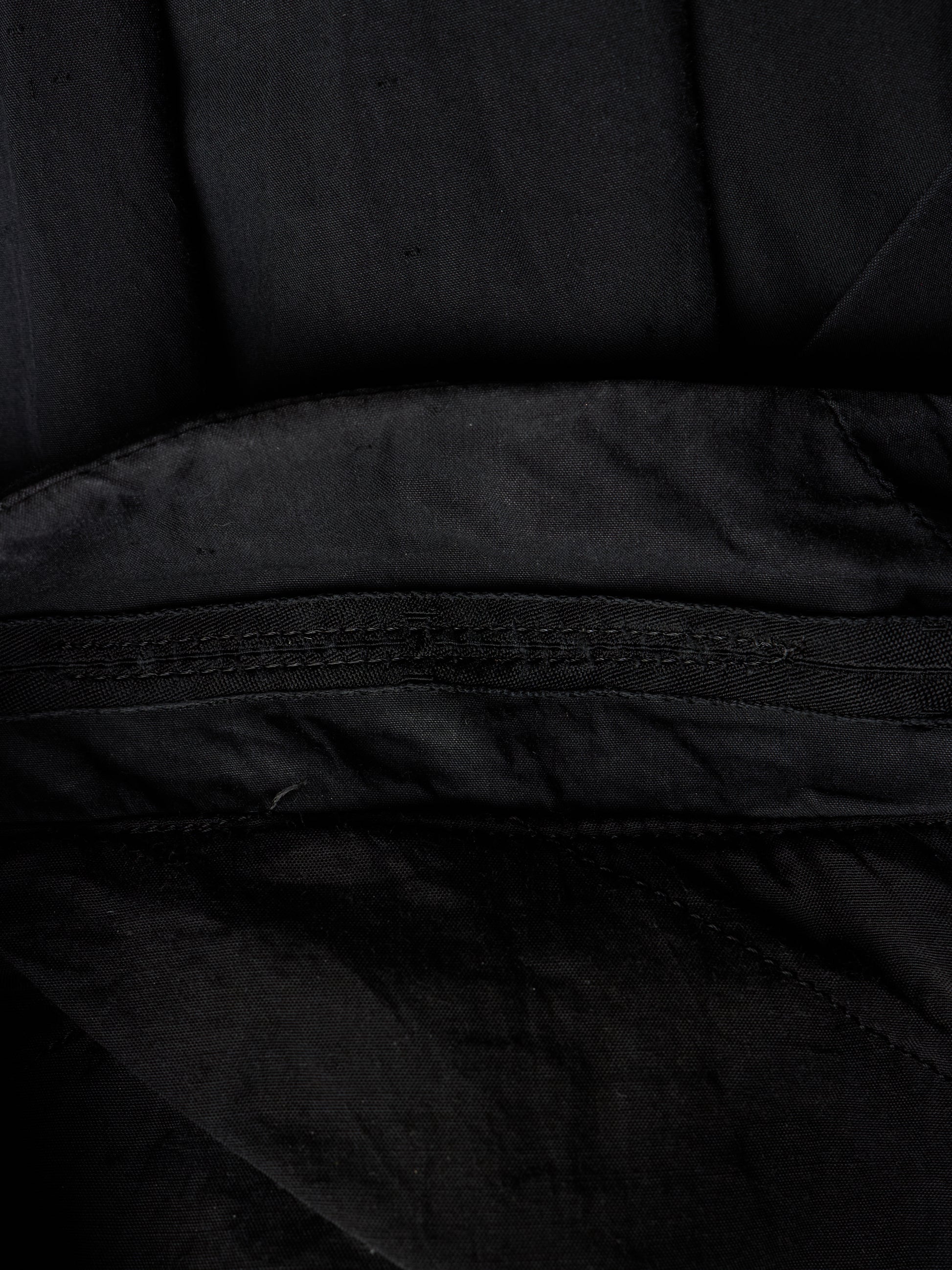 Close-up detail of a black fabric item showing a stitched seam and textured material.