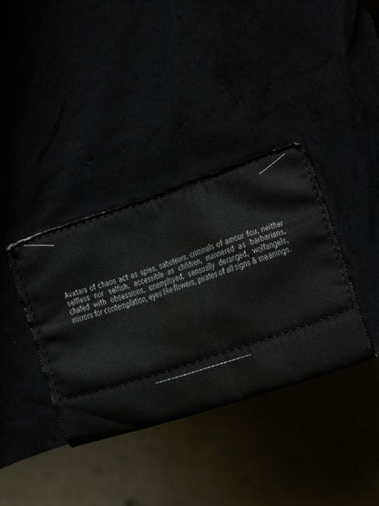 Close-up of a black garment showing a sewn-in fabric label with white text on the inside of a sleeve or cuff.