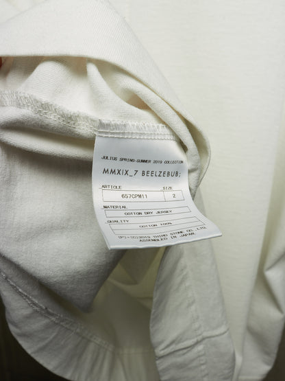Close-up of a cream-colored garment showing the inner neck label with text including 'JEANS SPRING-SUMMER COLLECTION MMXIX.7 BEEZBUB'.
