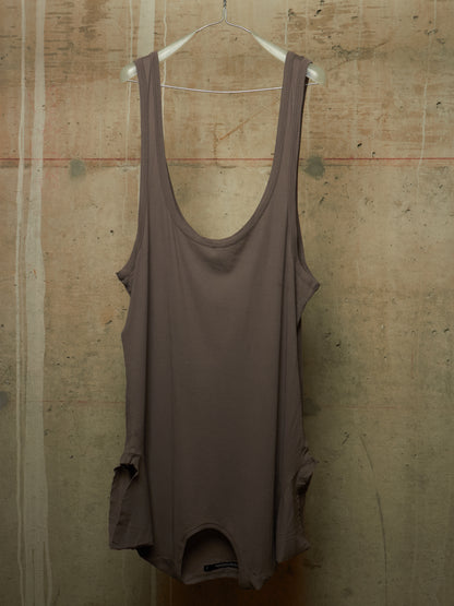A sleeveless scoop-neck tank top in a muted taupe-brown color, hanging on a white wire hanger against a textured concrete wall.