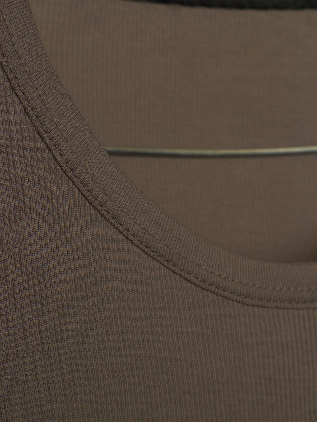 Close-up detail of a ribbed knit garment, showing the scoop neckline with double-stitched trim and a thin elastic band.