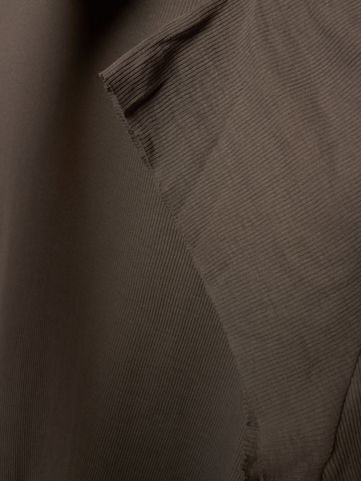 Close-up of a dark brown ribbed fabric texture with a diagonal fold and stitched edge.