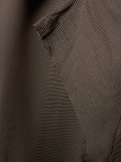 Close-up of a dark brown ribbed fabric texture with a diagonal fold and stitched edge.