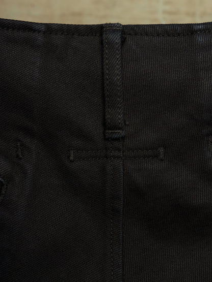 Close-up detail of black denim fabric showing the back waistband, belt loop, and stitching.